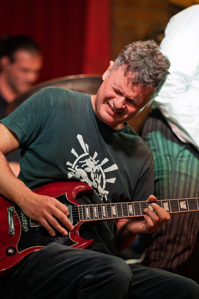 Guitarist digging into a solo on a red SG